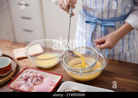 Femme essorant le liquide d'oeuf avec du bouillon. Banque D'Images
