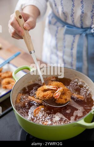 Femme faisant frire des crevettes frites dans l'huile Banque D'Images