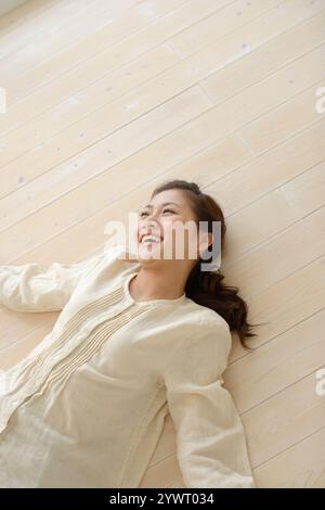 Jeune femme allongée sur un plancher en bois Banque D'Images