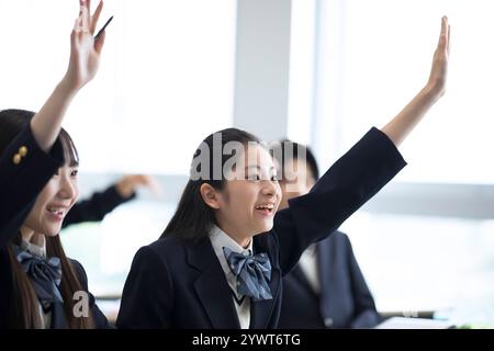 Des lycéens levant la main en classe Banque D'Images