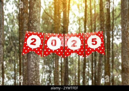 Texte de bonne année 2025 écrit sur papier suspendu avec fond d'arbres. Bonne année concept ou célébration Banque D'Images
