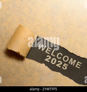 Vue de dessus de papier brun déchiré avec le texte de bienvenue 2025 écrit sur fond noir. Bonne année concept ou célébration Banque D'Images