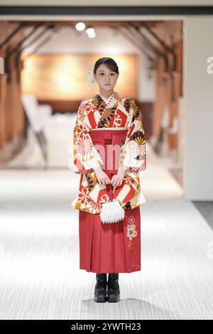 Une japonaise d'une vingtaine d'années se tient à l'intérieur portant un kimono rouge (hakama), un incontournable pour les diplômés d'université japonais. Banque D'Images