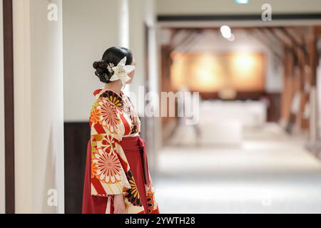 Une japonaise d'une vingtaine d'années se tient à l'intérieur portant un kimono rouge (hakama), un incontournable pour les diplômés d'université japonais. Banque D'Images