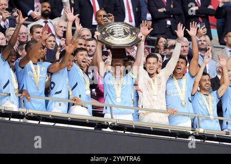 Photo du dossier datée du 10/08/24 des joueurs de Manchester City célébrant avec le bouclier communautaire après avoir battu Manchester United 7-6 aux pénalités après un tirage au sort de 1-1 à Wembley. Date d'émission : jeudi 12 décembre 2024. Banque D'Images