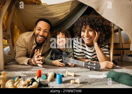 Portrait d'une famille joyeuse de trois passe du temps de qualité à l'intérieur d'un fort de couverture confortable, souriant et profitant d'activités de jeu. Banque D'Images