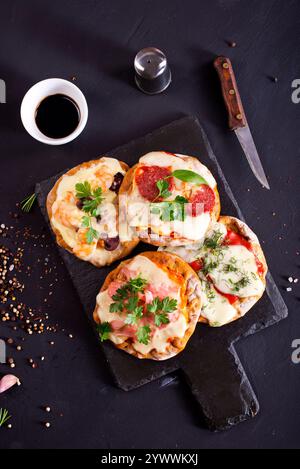 Mini pizzas - pizzeria - nappées de fromage et de tomates, de jambon italien et de piment Banque D'Images