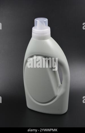 Une grande bouteille grise pour laver les vêtements, linge de lit, tissus. Une bouteille en plastique remplie d'un liquide visqueux violet avec un bouchon transparent. Banque D'Images