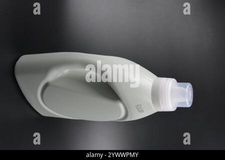 Une grande bouteille grise pour laver les vêtements, linge de lit, tissus. Une bouteille en plastique remplie d'un liquide visqueux violet avec un bouchon transparent. Banque D'Images