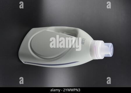 Une grande bouteille grise pour laver les vêtements, linge de lit, tissus. Une bouteille en plastique remplie d'un liquide visqueux violet avec un bouchon transparent. Banque D'Images