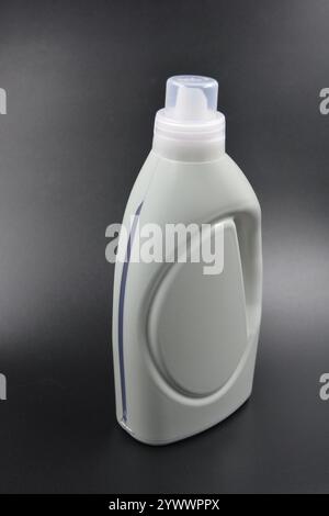 Une grande bouteille grise pour laver les vêtements, linge de lit, tissus. Une bouteille en plastique remplie d'un liquide visqueux violet avec un bouchon transparent. Banque D'Images