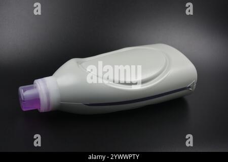 Une grande bouteille grise pour laver les vêtements, linge de lit, tissus. Une bouteille en plastique remplie d'un liquide visqueux violet avec un bouchon transparent. Banque D'Images