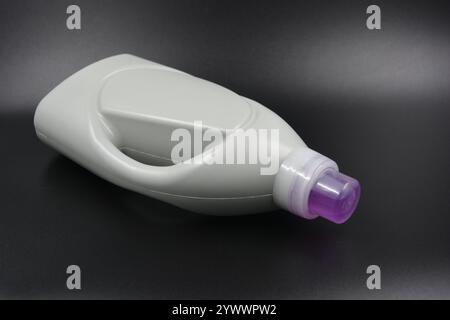 Une grande bouteille grise pour laver les vêtements, linge de lit, tissus. Une bouteille en plastique remplie d'un liquide visqueux violet avec un bouchon transparent. Banque D'Images