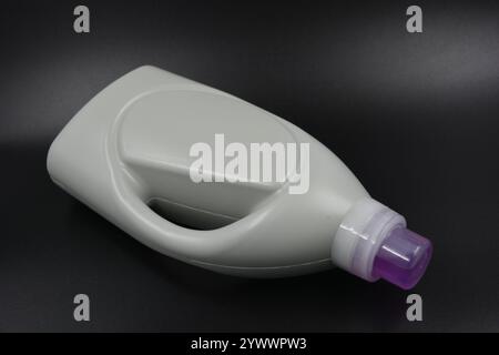 Une grande bouteille grise pour laver les vêtements, linge de lit, tissus. Une bouteille en plastique remplie d'un liquide visqueux violet avec un bouchon transparent. Banque D'Images
