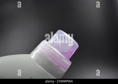 Une grande bouteille grise pour laver les vêtements, linge de lit, tissus. Une bouteille en plastique remplie d'un liquide visqueux violet avec un bouchon transparent. Banque D'Images