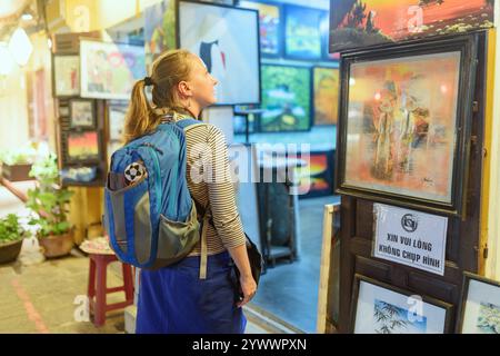Touriste femme regardant des peintures dans un magasin d'art, Hoi an Banque D'Images