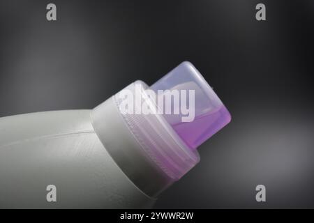 Une grande bouteille grise pour laver les vêtements, linge de lit, tissus. Une bouteille en plastique remplie d'un liquide visqueux violet avec un bouchon transparent. Banque D'Images