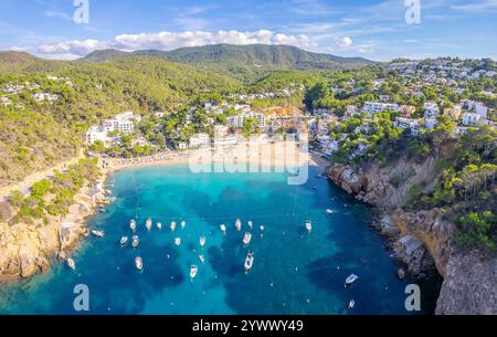 Vue aérienne de Cala Vadella, Ibiza, avec des eaux turquoises, des voiliers, des plages de sable, et villas de luxe Banque D'Images