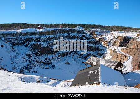 La neige recouvre la mine de Falun, soulignant son importance historique. Les bâtiments au sommet du site ajoutent à la scène hivernale pittoresque de Dalarna, en Suède. Banque D'Images