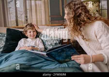 Cozy matin de Noël lisant un livre par la fenêtre avec la famille dans une chambre chaleureuse et accueillante Banque D'Images