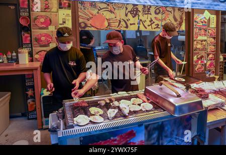 Hommes préparant des fruits de mer dans un restaurant au bord de la route dans la zone extérieure du marché de Tsukiji, Tsukiji, Chuo City, Tokyo, Japon, Asie. Banque D'Images