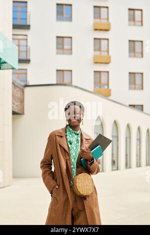 Femme souriante portant un pardessus marron tenant livre Banque D'Images