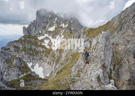 Alpinistes sur un étroit sentier de randonnée sur une crête rocheuse, ascension vers le Maukspitze, nuages se déplaçant autour des montagnes, Ackerlpitze en arrière-plan, W Banque D'Images