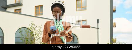 Jeune femme portant un casque vérifiant le téléphone tout en faisant du vélo Banque D'Images