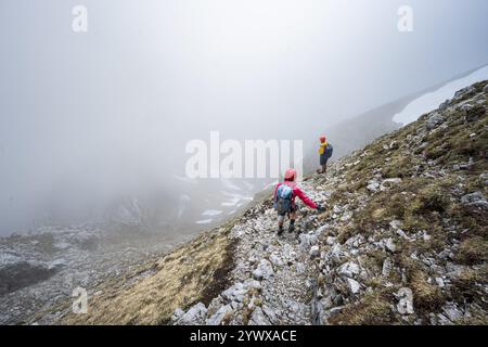 Deux alpinistes sur un étroit sentier de randonnée, ascension à l'Ackerlspitze, nuages se déplaçant autour des montagnes, Wilder Kaiser, montagnes Kaiser, Tyrol, Aus Banque D'Images