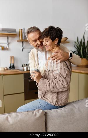 Un couple aimant partage un moment calme dans leur maison chaleureuse et accueillante tout en sirotant des boissons. Banque D'Images