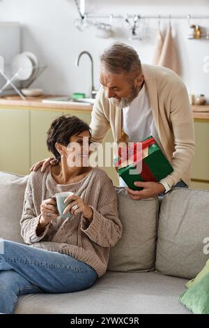 Couple profite d'un moment réconfortant ensemble pendant que des cadeaux sont échangés dans leur cuisine élégante. Banque D'Images