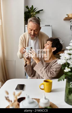 Couple senior partage un moment chaleureux autour d'un café dans leur espace cuisine lumineux et accueillant. Banque D'Images