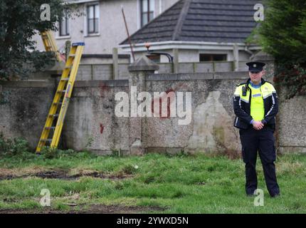 Un officier de la Garda se tient près d'une propriété sur Beechwood Drive à Drogheda, où la police effectue une fouille médico-légale en relation avec la disparition de Kyran Durnin, de Co Louth. Un homme est détenu parce qu'il est soupçonné du meurtre de l'écolier irlandais. Jeudi, des policiers ont lancé des perquisitions dans deux maisons à Drogheda dans le but de découvrir toute preuve qui pourrait révéler où se trouve Kyran ou ce qui lui est arrivé. Date de la photo : jeudi 12 décembre 2024. Banque D'Images