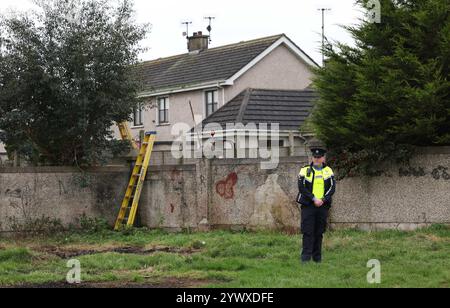 Un officier de la Garda se tient près d'une propriété sur Beechwood Drive à Drogheda, où la police effectue une fouille médico-légale en relation avec la disparition de Kyran Durnin, de Co Louth. Un homme est détenu parce qu'il est soupçonné du meurtre de l'écolier irlandais. Jeudi, des policiers ont lancé des perquisitions dans deux maisons à Drogheda dans le but de découvrir toute preuve qui pourrait révéler où se trouve Kyran ou ce qui lui est arrivé. Date de la photo : jeudi 12 décembre 2024. Banque D'Images