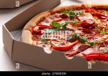 Grande Pizza avec pepperoni et poivrons dans la boîte de carton ouverte vue rapprochée Banque D'Images