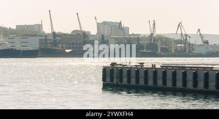 Vladivostok, Russie - 21 octobre 2012 : un port animé avec des grues et des navires sous un ciel brumeux. Banque D'Images