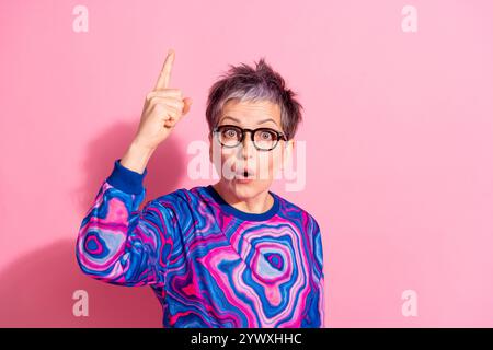 Portrait photo de la femme senior attrayante pointe vers le haut eureka habillé vêtements colorés bleus isolés sur fond de couleur rose Banque D'Images