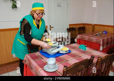 Une femme qui nettoyait la table à partir de plats sales après que les personnes âgées pauvres aient eu le repas gratuit. Centre de services sociaux. 6 avril 2018. Kiev, Ukraine Banque D'Images