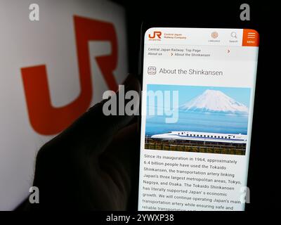 Dans cette illustration photo, une personne tient un téléphone portable avec la page Web de l'entreprise ferroviaire japonaise Central Japan Railway Company avec logo. Banque D'Images