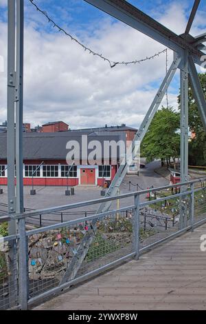 Les serrures d'amour accrochées à la balustrade sur le pont piétonnier au-dessus de la rivière Vantaajoki à Vanhankaupunginkoski en été avec des nuages dans le ciel, Helsinki, Finlande. Banque D'Images