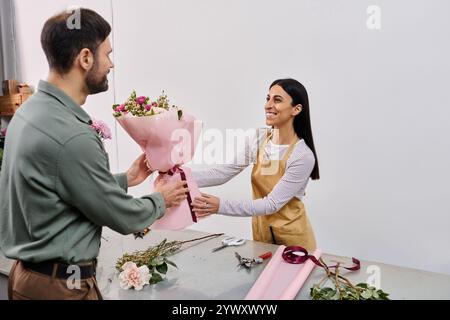 Un fleuriste habile s'engage avec un client masculin tout en arrangeant des fleurs vibrantes dans la boutique. Banque D'Images