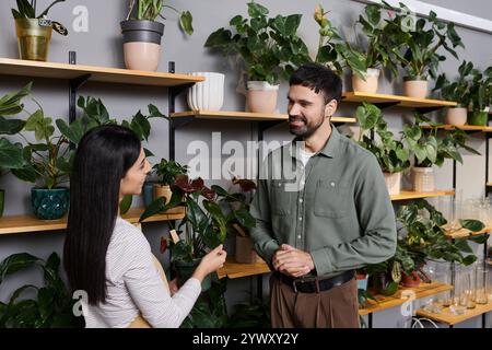 Fleuriste professionnel s'engage avec un client masculin dans une boutique dynamique et écologique. Banque D'Images