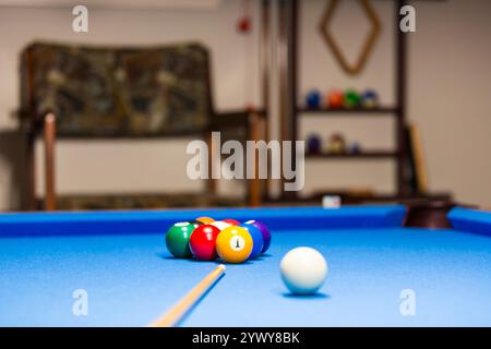 Boules de billard sur une table bleue. L'image montre un ensemble de boules de billard brillantes méticuleusement disposées dans un rack triangulaire sur un feutre bleu immaculé. Banque D'Images