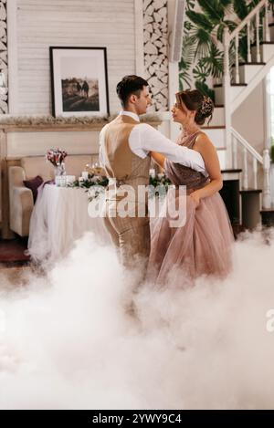 la première danse de la mariée et du marié à l'intérieur d'un restaurant avec beaucoup de fumée Banque D'Images