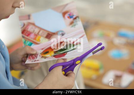 Création d'un tableau de vision. Petit garçon découpant la photo à l'intérieur, gros plan Banque D'Images