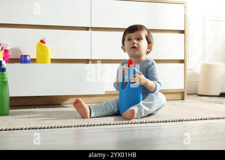 Petit garçon jouant avec des bouteilles de détergents près de l'armoire à la maison. Enfant en danger Banque D'Images