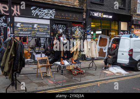 Londres, Royaume-Uni, 1er décembre 2024, dimanche sur Brick Lane. Marché aux puces. Un vendeur est assis dans une voiture à côté des articles qu'il vend. Banque D'Images