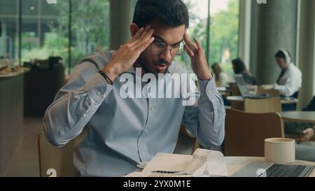 Homme d'affaires bouleversé problème de paperasse Indien Arabique homme d'affaires visiteur dans le café homme triste frustré gars anxieux travail indépendant ordinateur portable fatigué stress Banque D'Images