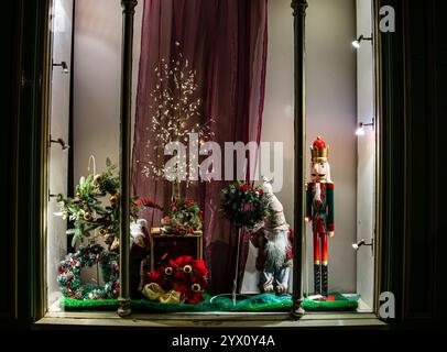Vitrine élégante des fêtes avec casse-noix, décorations festives et ornements lumineux sur fond de rideau violet Banque D'Images