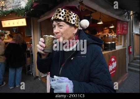 New York, États-Unis. 12 décembre 2024. Une femme portant un chapeau de Père Noël boit un chocolat chaud alors qu'elle se promène dans le marché de vacances installé à Union Square, New York, NY, le 12 décembre 2024. Les pop-shops annuels des fêtes de Noël sont installés à Union Square ainsi que Columbus Circle et Bryant Park offrant des articles sur le thème des fêtes à vendre. (Photo par Anthony Behar/Sipa USA) crédit : Sipa USA/Alamy Live News Banque D'Images